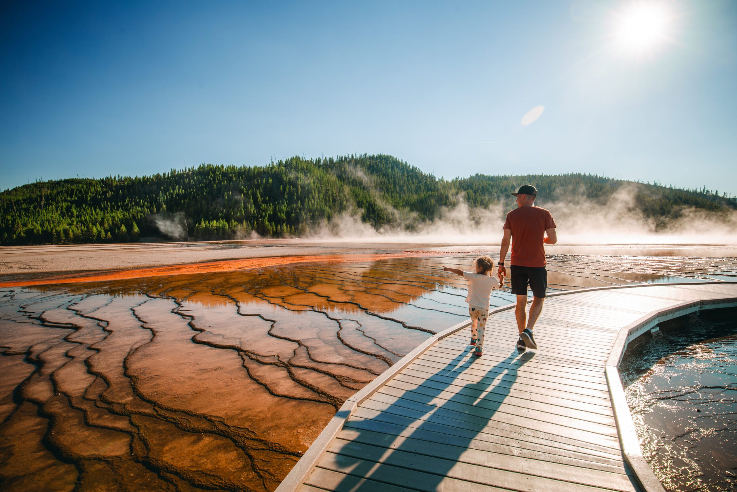Father and child walking near geyser at Yellowstone national park
