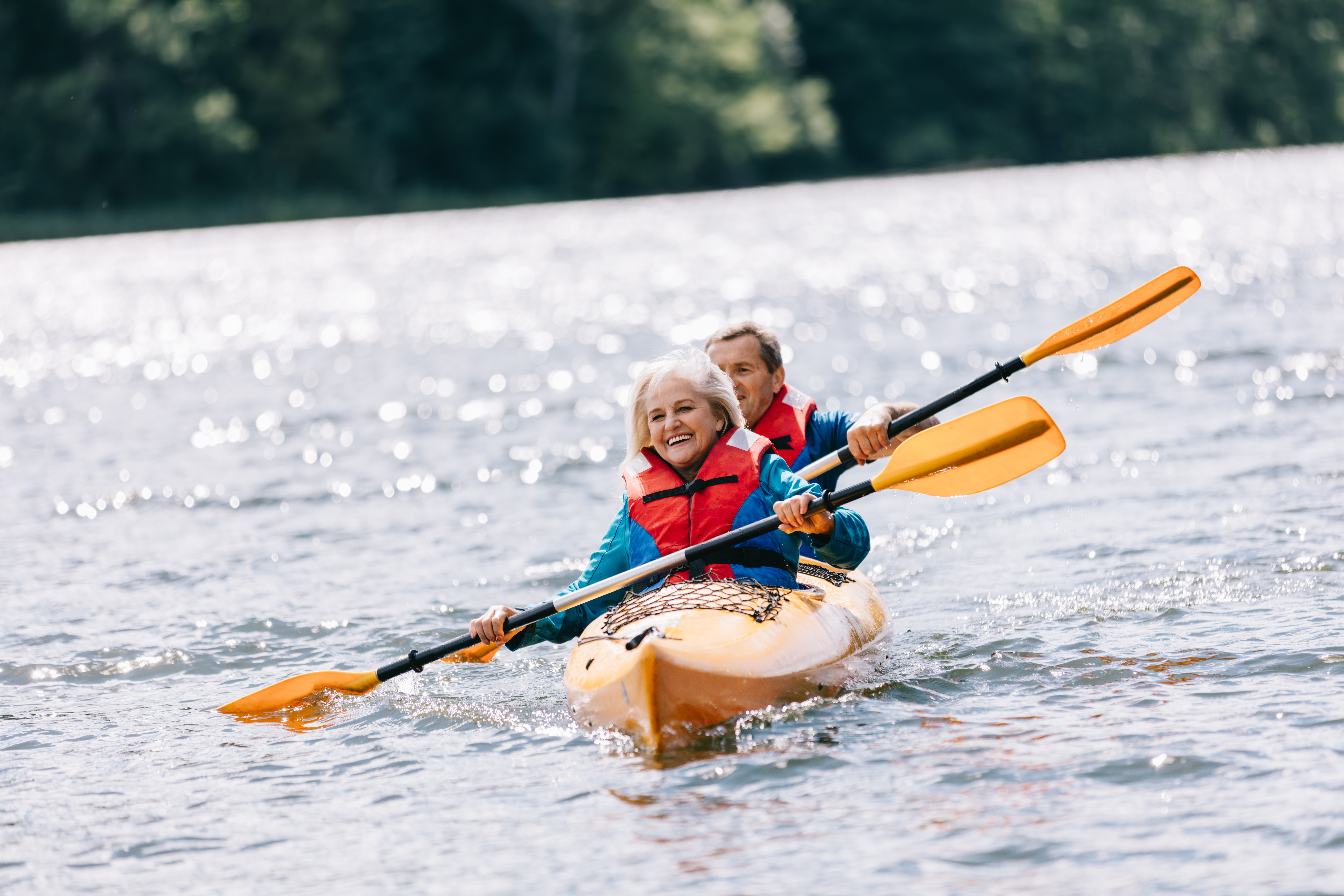 Happy senior active couple kayaking on lake